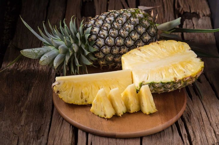 Ripe pineapple and pineapple slices on a wooden background tropical fruits.