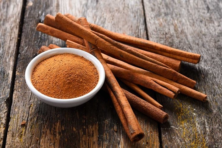 Cinnamon sticks and cinnamon powder on wood