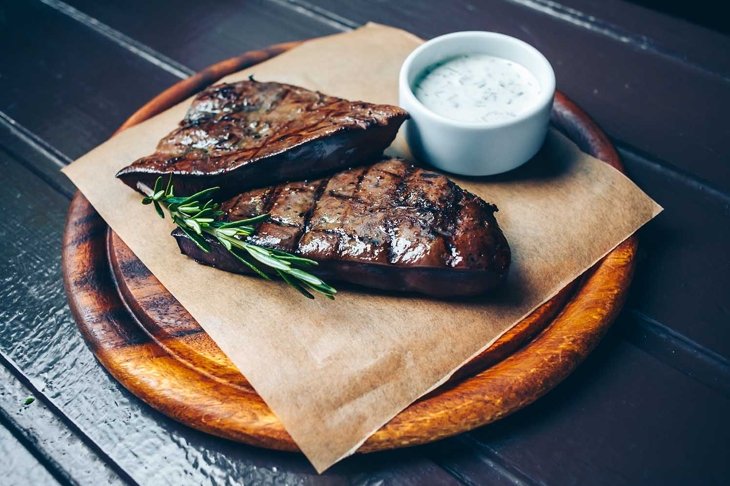 Grilled beef liver on the wooden plate.